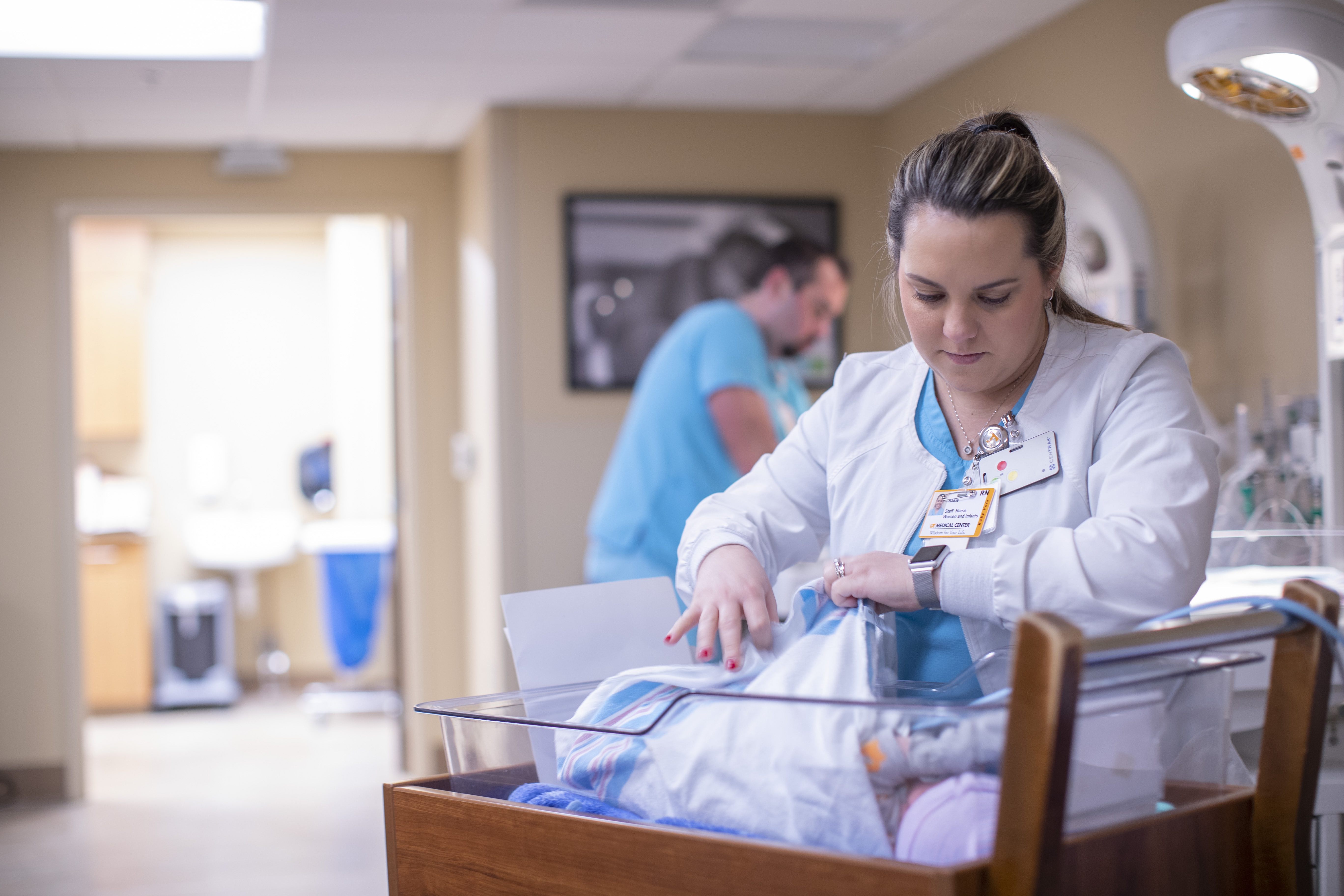 nurse with newborn infant in crib