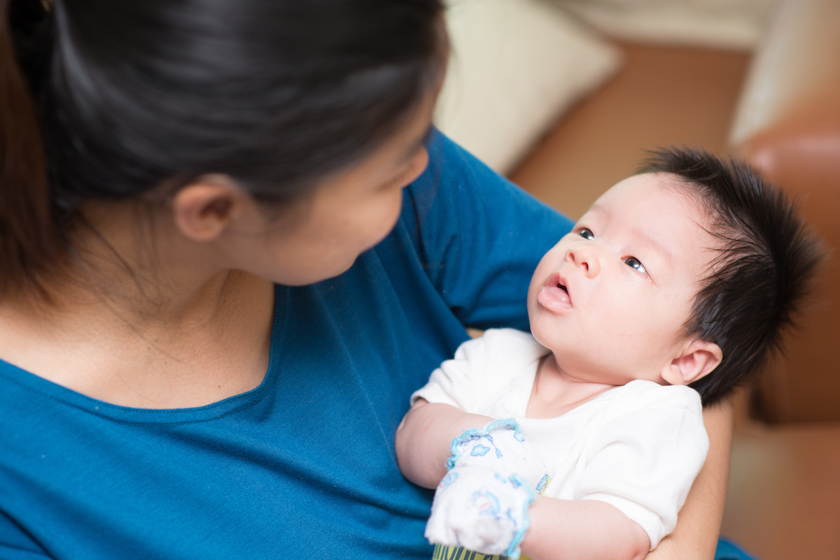 woman looking down at infant in her arms