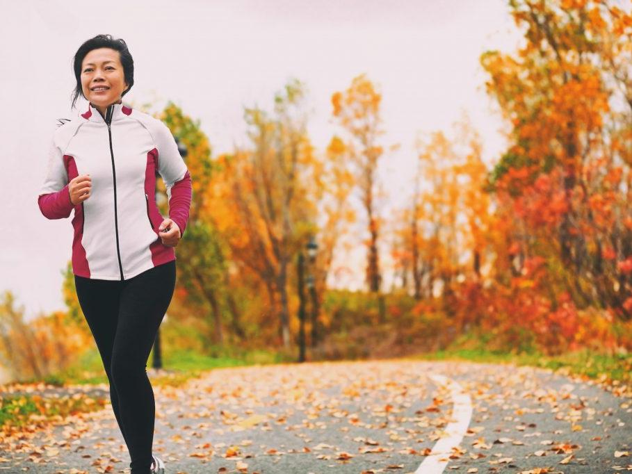A woman jogs on a park trail in autumn