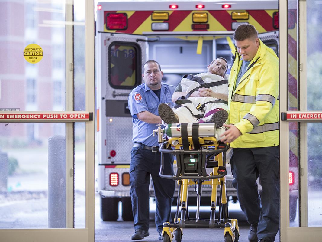 EMTs roll a patient on a stretcher from an ambulance to the Emergency Department