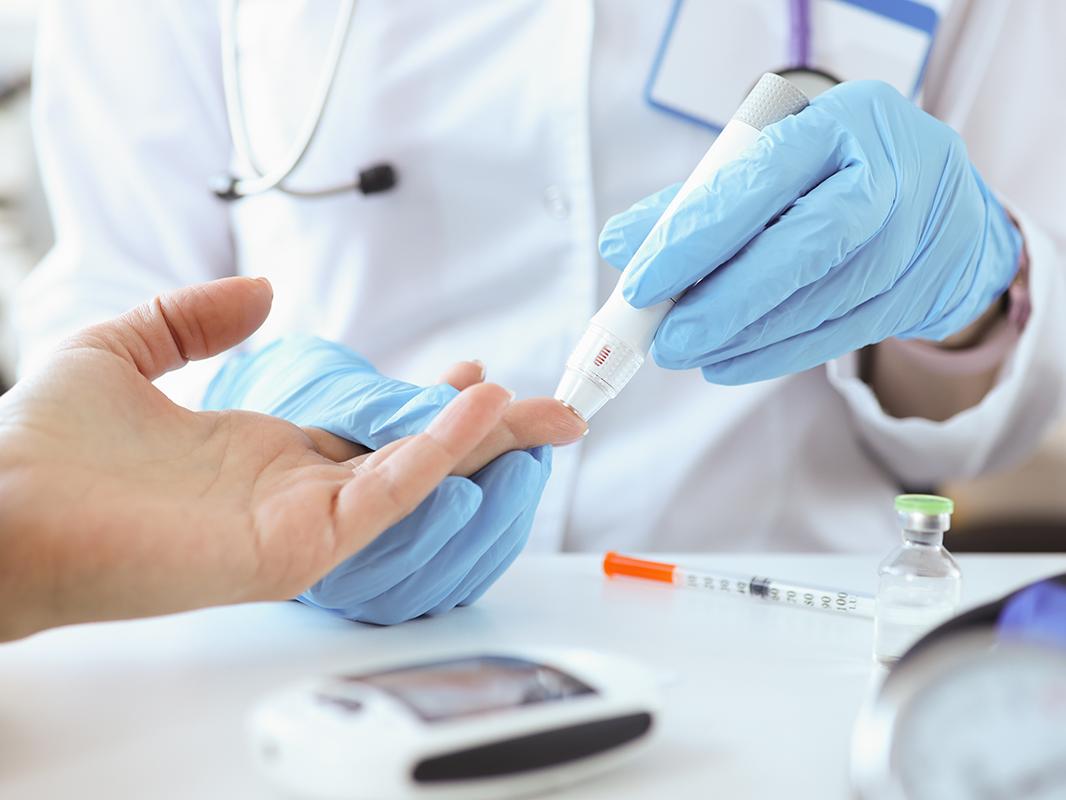 A medical professional sticks a patient's finger for a blood draw