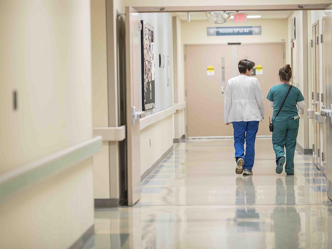 Two medical professionals walk down a hospital hallway