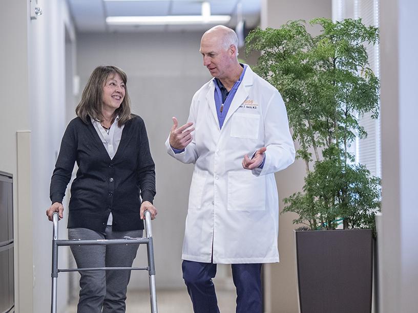 Orthopaedic doctor talking with patient using a walker