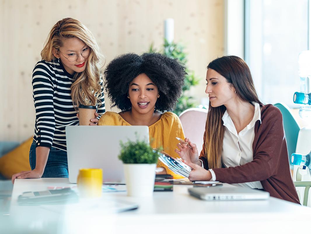 Three women look at a laptop