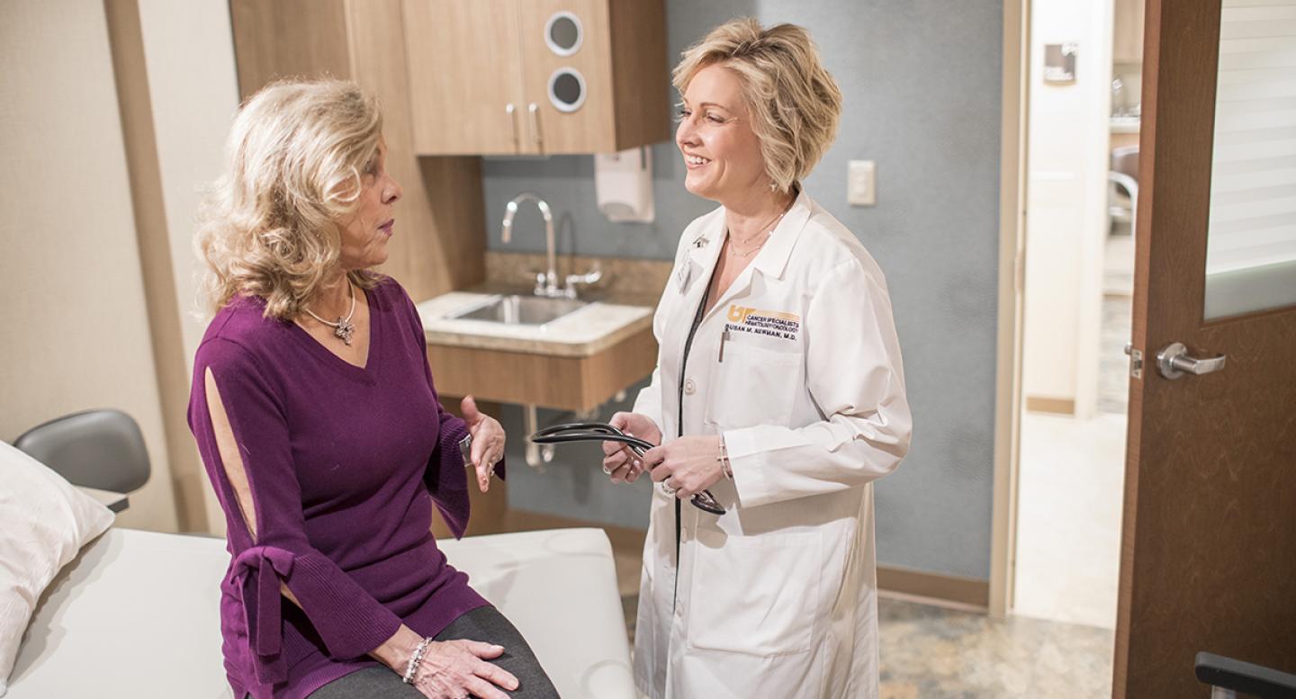 A female doctor talks with a female patient in an exam room