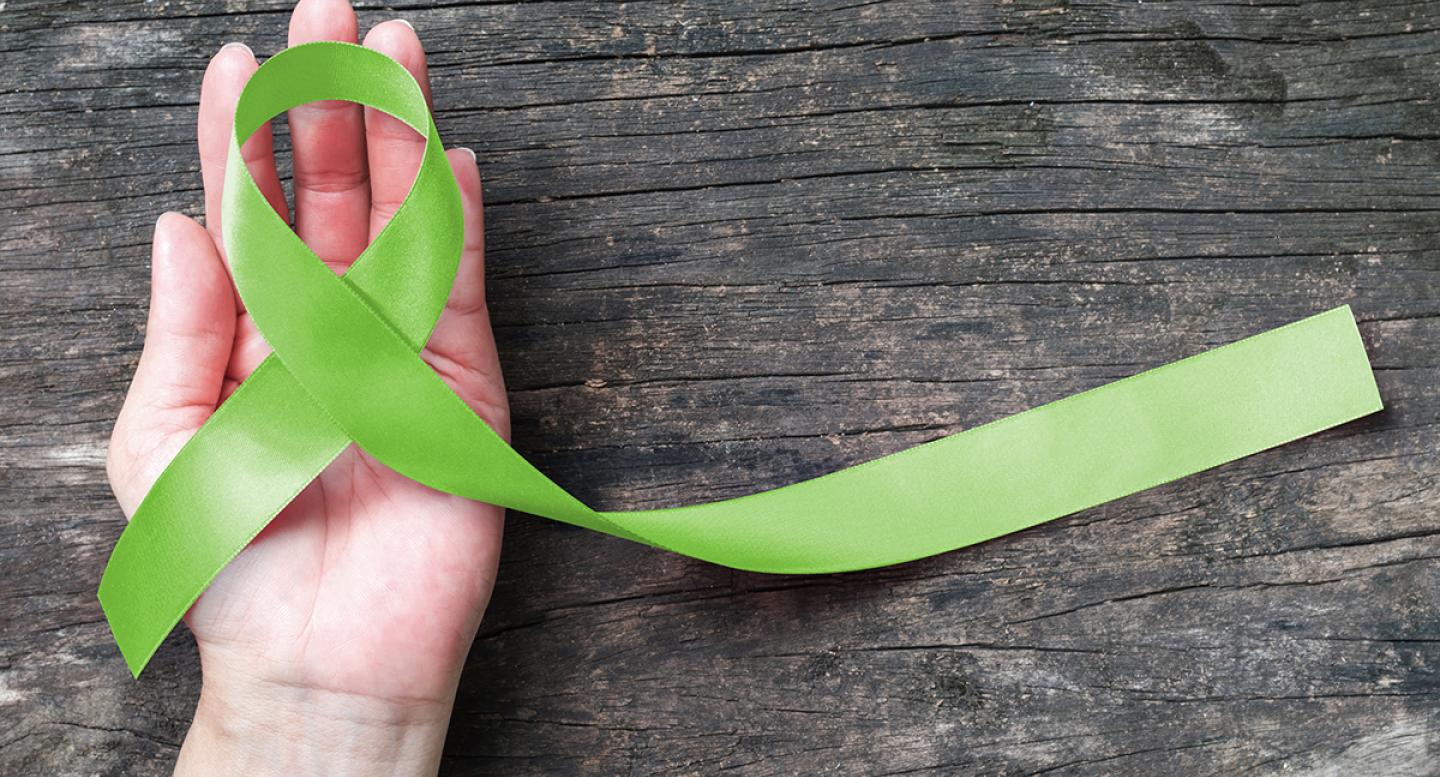 Hand holding green ribbon for lymphedema