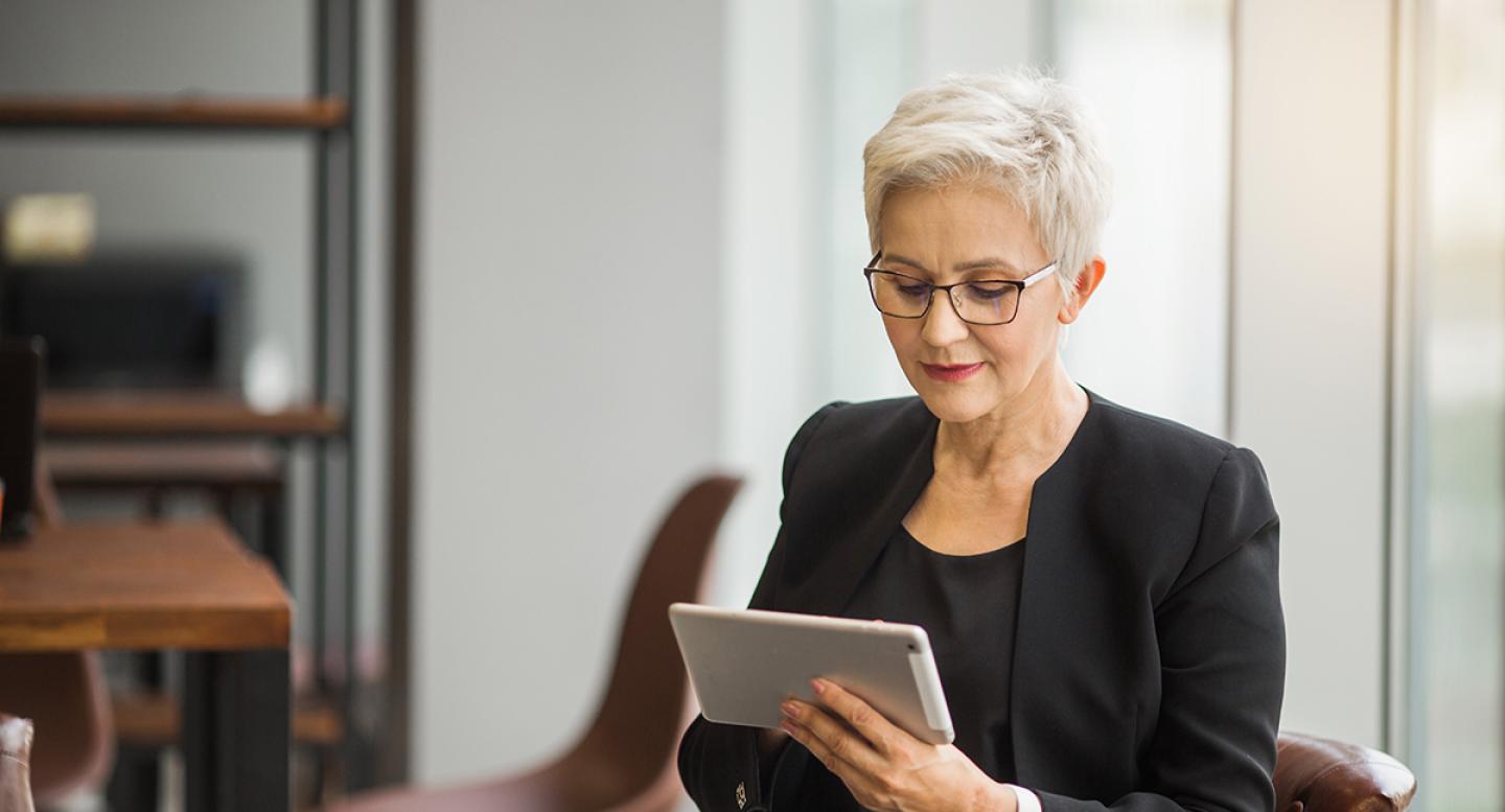 A silver-haired business woman reads a tablet