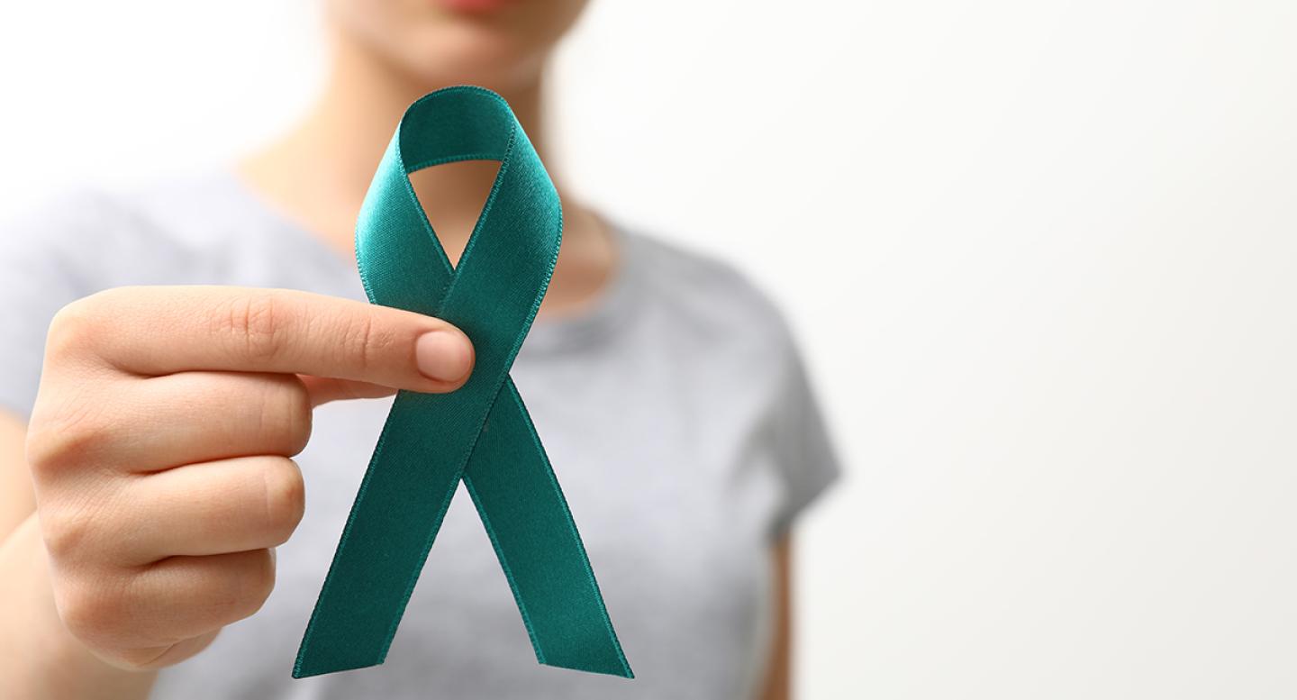 A woman holds a teal ribbon for ovarian cancer