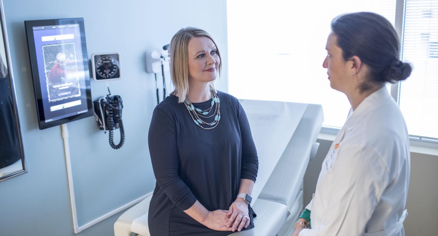 A breast cancer patient talks with a doctor in an exam room