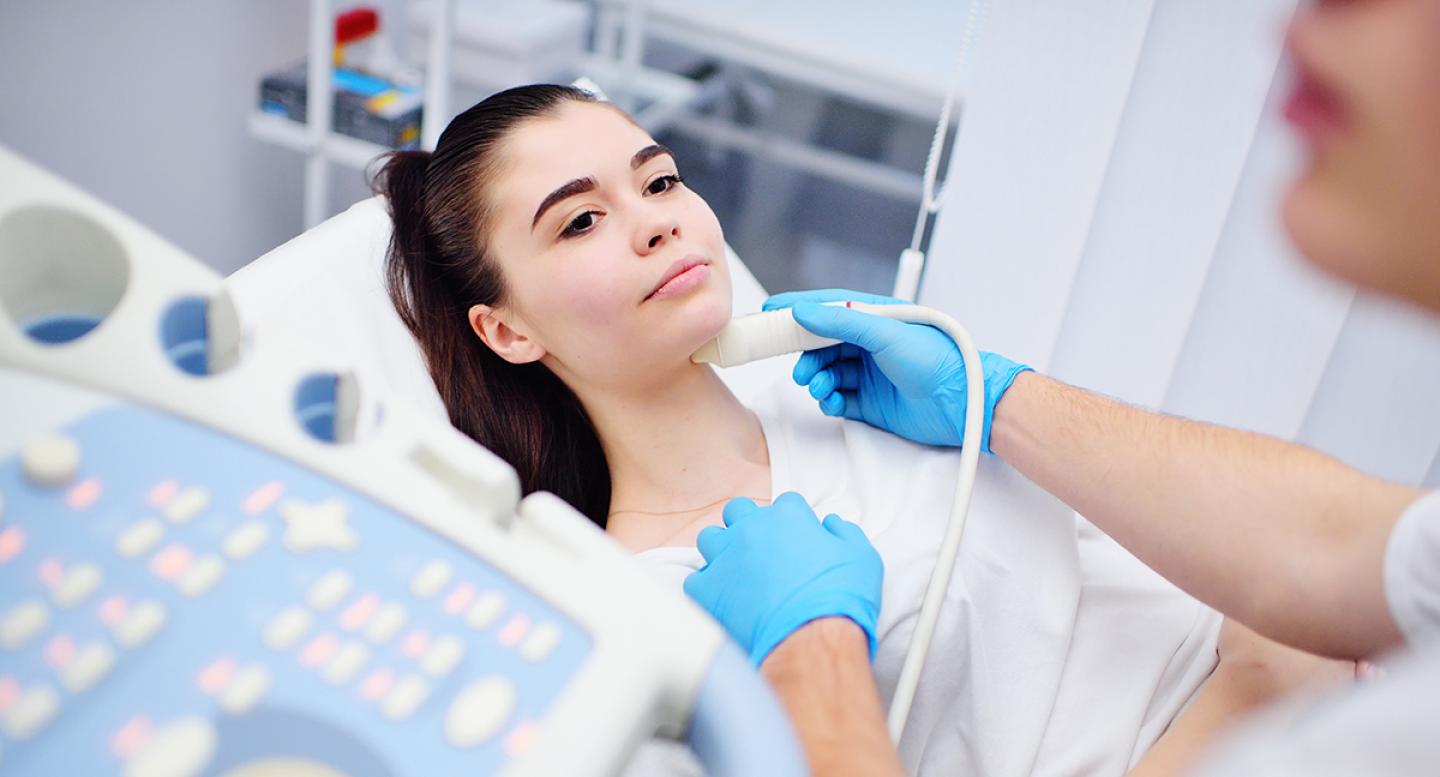 A young woman receives a thyroid scan