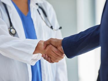 A female doctor shakes the hand of a man in a suit