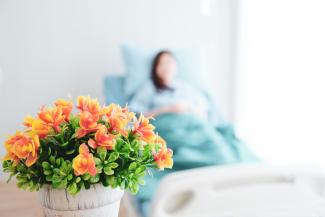 A bouquet of flowers with a woman in a hospital bed in the background