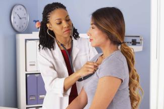 A doctor checks a patient's heartbeat with a stethoscope