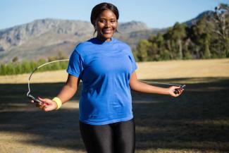 A Black woman jumps rope in the park