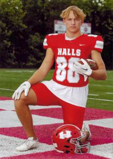 A young adult poses in his football uniform