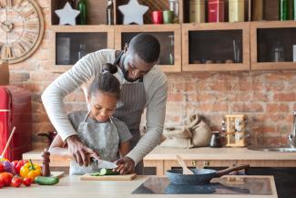 A father and daughter cook together in the kitchen