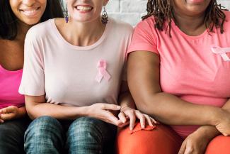 Three women wearing pink breast cancer ribbons