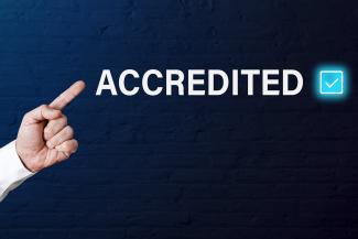 A finger points at the word "accredited"