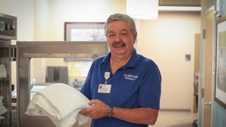 A volunteer holds a blanket from a blanket warmer