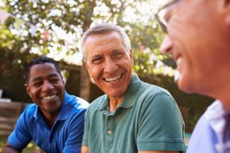 Three older men laughing in a park