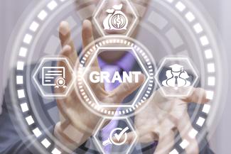 A man points toward graphics with the word "grant" in the middle