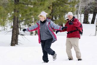 A senior couple hikes in snowy woods