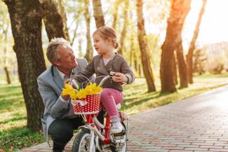 A man helps a little girl ride a bicycle