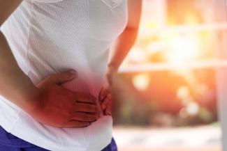 A woman doubles over clutching her stomach