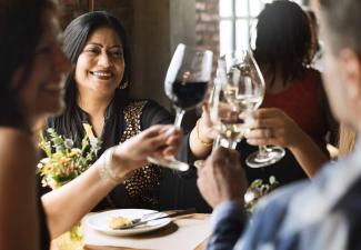 A group of women at dinner toast with their wine glasses