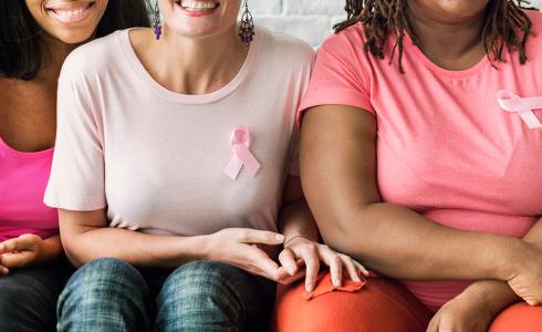 Three women wearing pink breast cancer ribbons