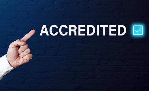 A finger points at the word "accredited"