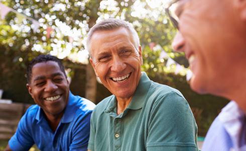Three older men laughing in a park