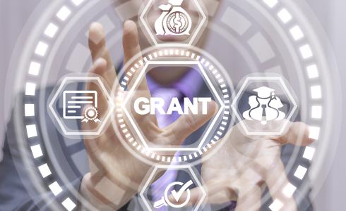 A man points toward graphics with the word "grant" in the middle