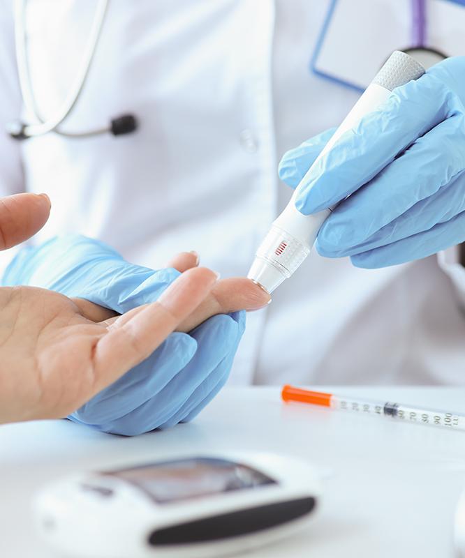 A medical professional sticks a patient's finger for a blood draw