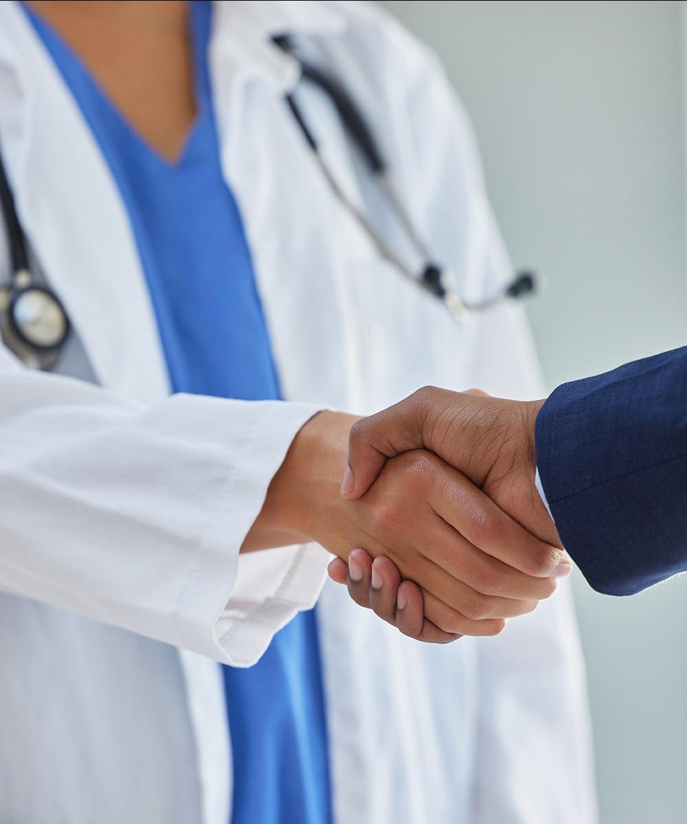 A female doctor shakes the hand of a man in a suit